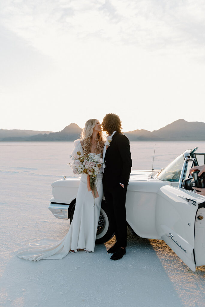 a romantic bride and groom with a vintage car during their bonneville salt flats elopement