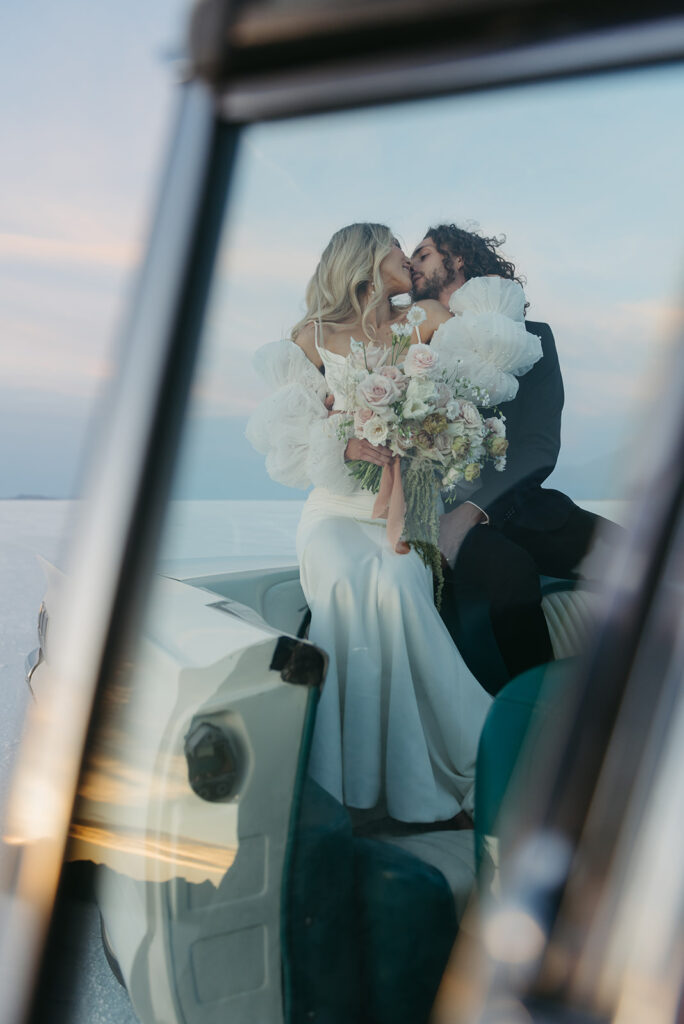 a romantic bride and groom with a vintage car during their bonneville salt flats elopement