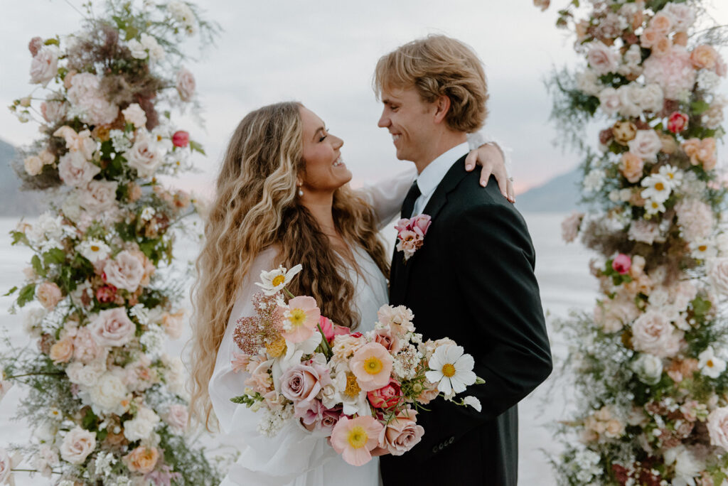 happy bride and groom gazing upon each other at their beautiful floral arch set up for their salt flats elopement