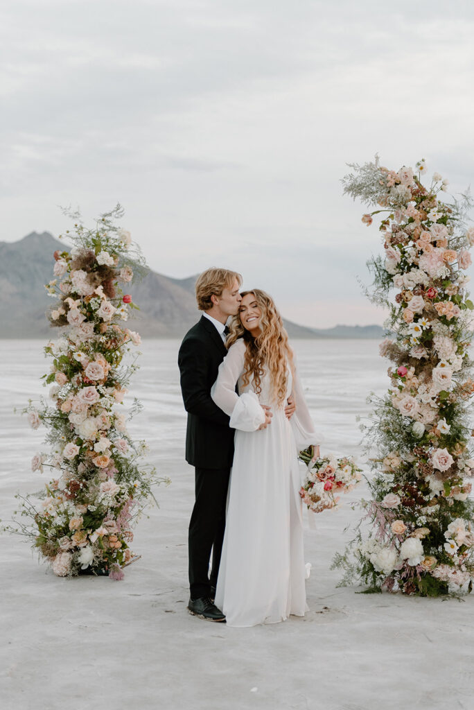 bride and groom standing at gorgeous floral arch during their salt flats elopement