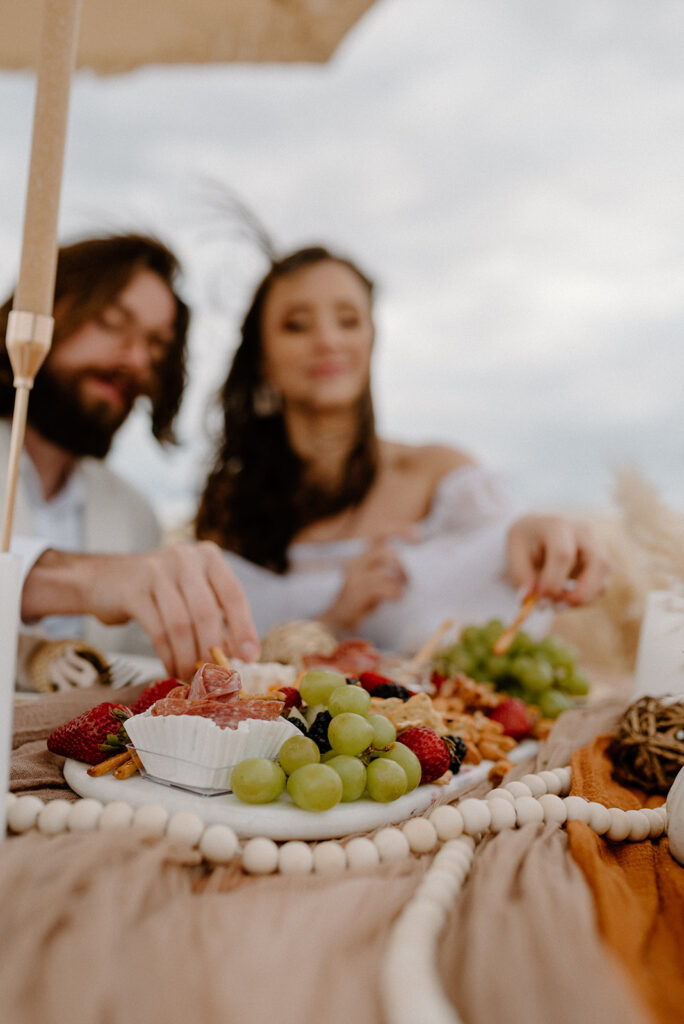 couple enjoying a charcuterie board during their boho Outer Banks elopement day