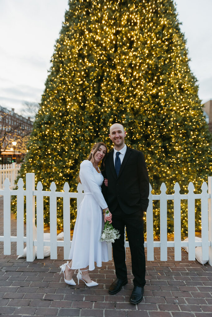 winter elopement in an old city with a sparkling christmas tree in the background