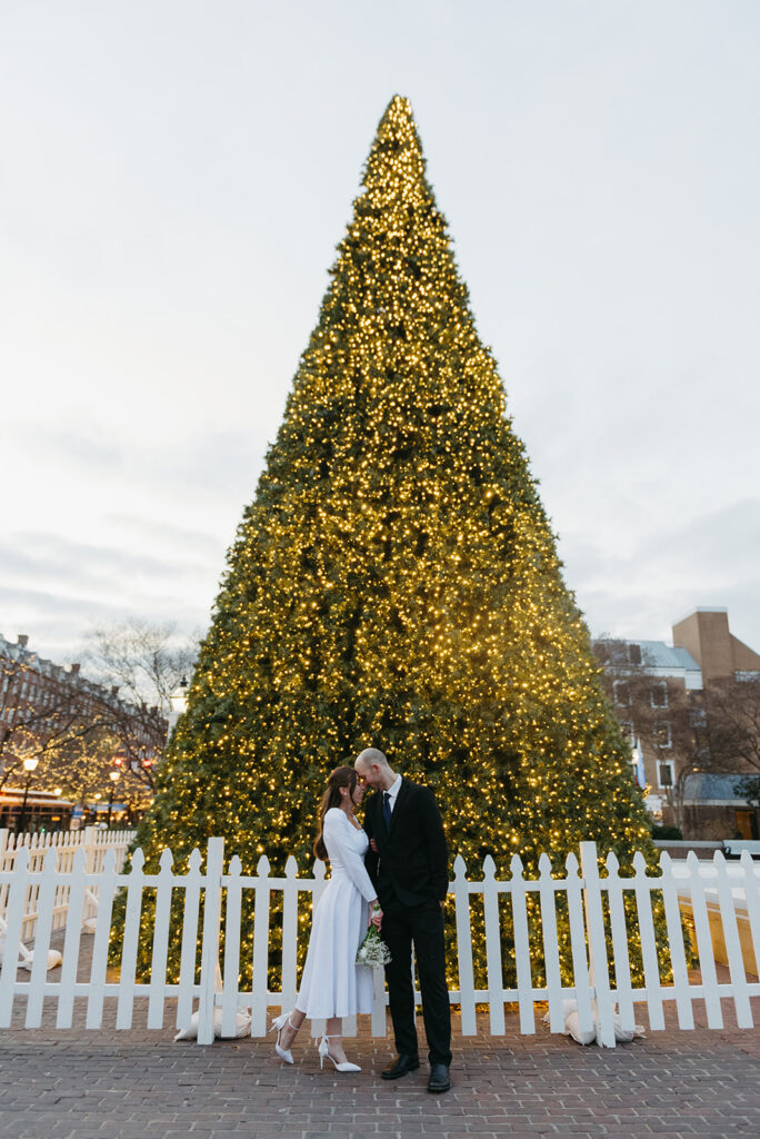 winter elopement in an old city with a sparkling christmas tree in the background