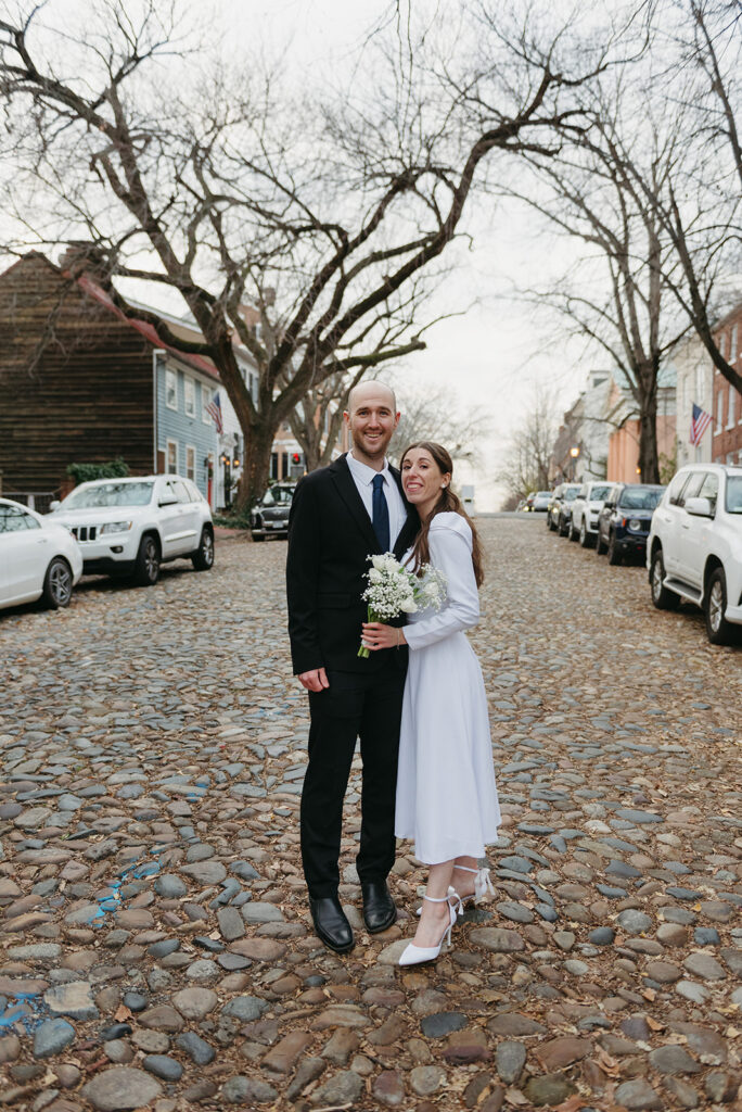 elegant elopement couple standing on a cobblestone street during their winter old town alexandria wedding elopement