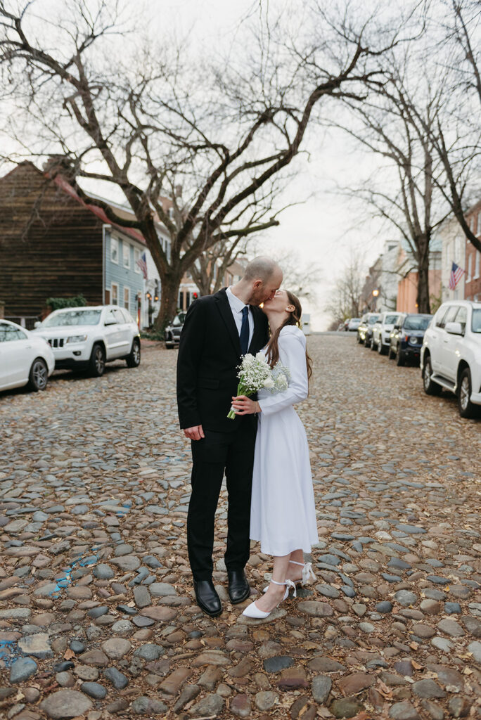 elegant elopement couple standing on a cobblestone street during their winter old town alexandria wedding elopement