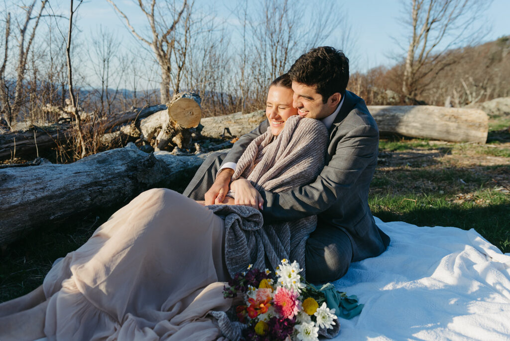 snuggly elopement couple under a blanket during their outdoor adventure elopement day in shenandoah national park 